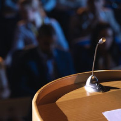 close-up-of-podium-with-speaker-in-auditorium-2021-08-28-16-47-40-utc